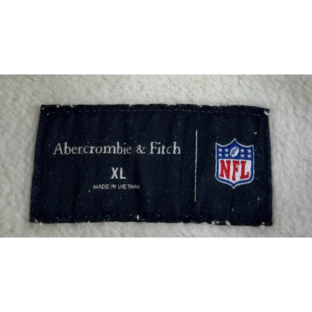 Second Half Supply Co, LLC Abercrombie & Fitch NFL hoodie size XL clothing tag detail on off-white fleece fabric