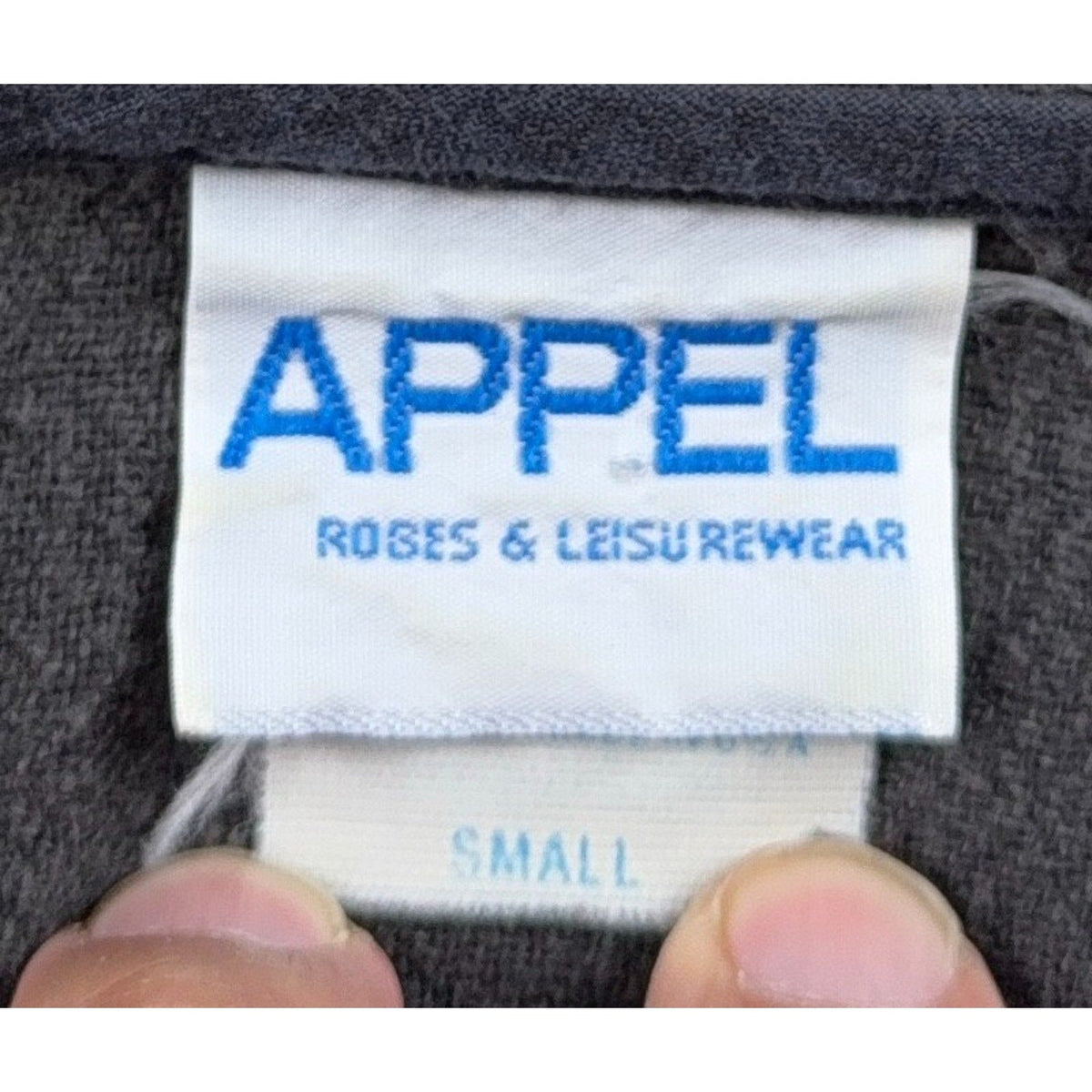 Second Half Supply Co, LLC vintage Appel Robes & Leisurewear clothing label on charcoal gray textured fabric
