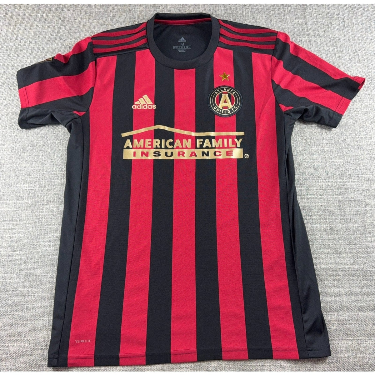 Second Half Supply Co, LLC Atlanta United FC 2019 home soccer jersey in red and black stripes with gold accents.