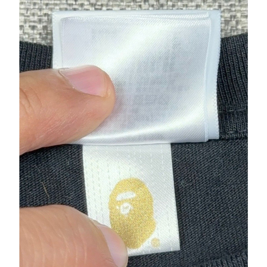 Second Half Supply Co, LLC BAPE t-shirt interior neck label with gold Ape Head logo on a white fabric tag