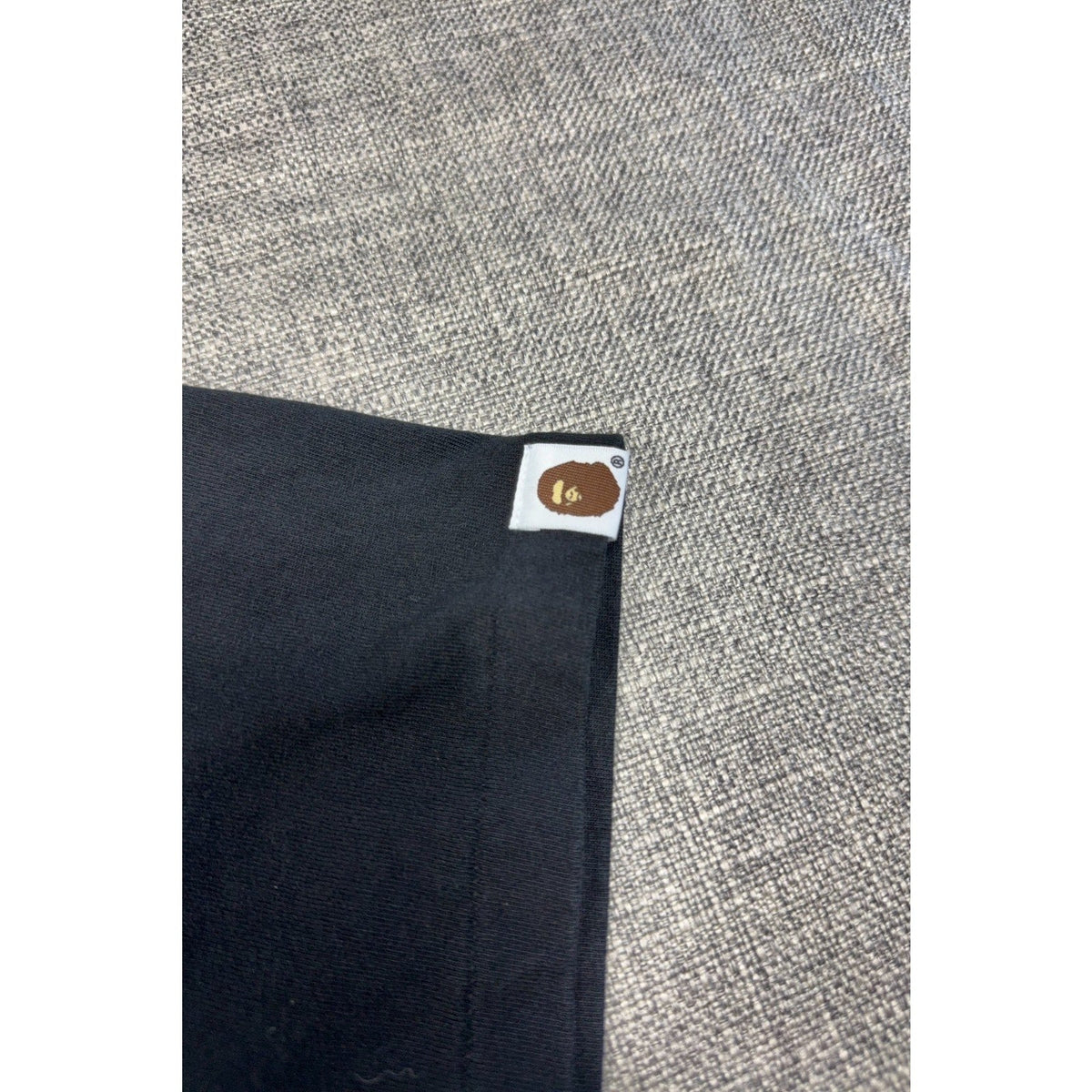 Second Half Supply Co, LLC black BAPE cotton t-shirt sleeve featuring a small woven Ape Head logo tab