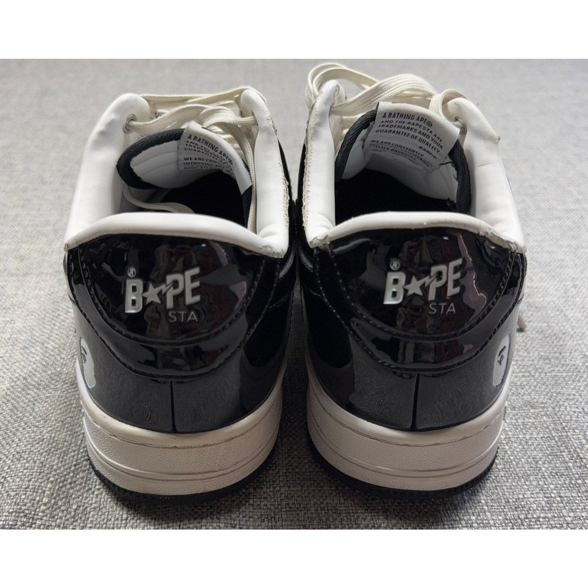 Second Half Supply Co, LLC black and white patent leather BAPE STA low-top sneakers, rear view showing heel branding.