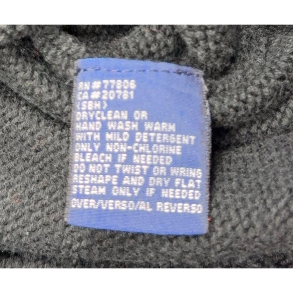 Second Half Supply Co, LLC blue care label on a dark green cotton knit sweater with washing instructions