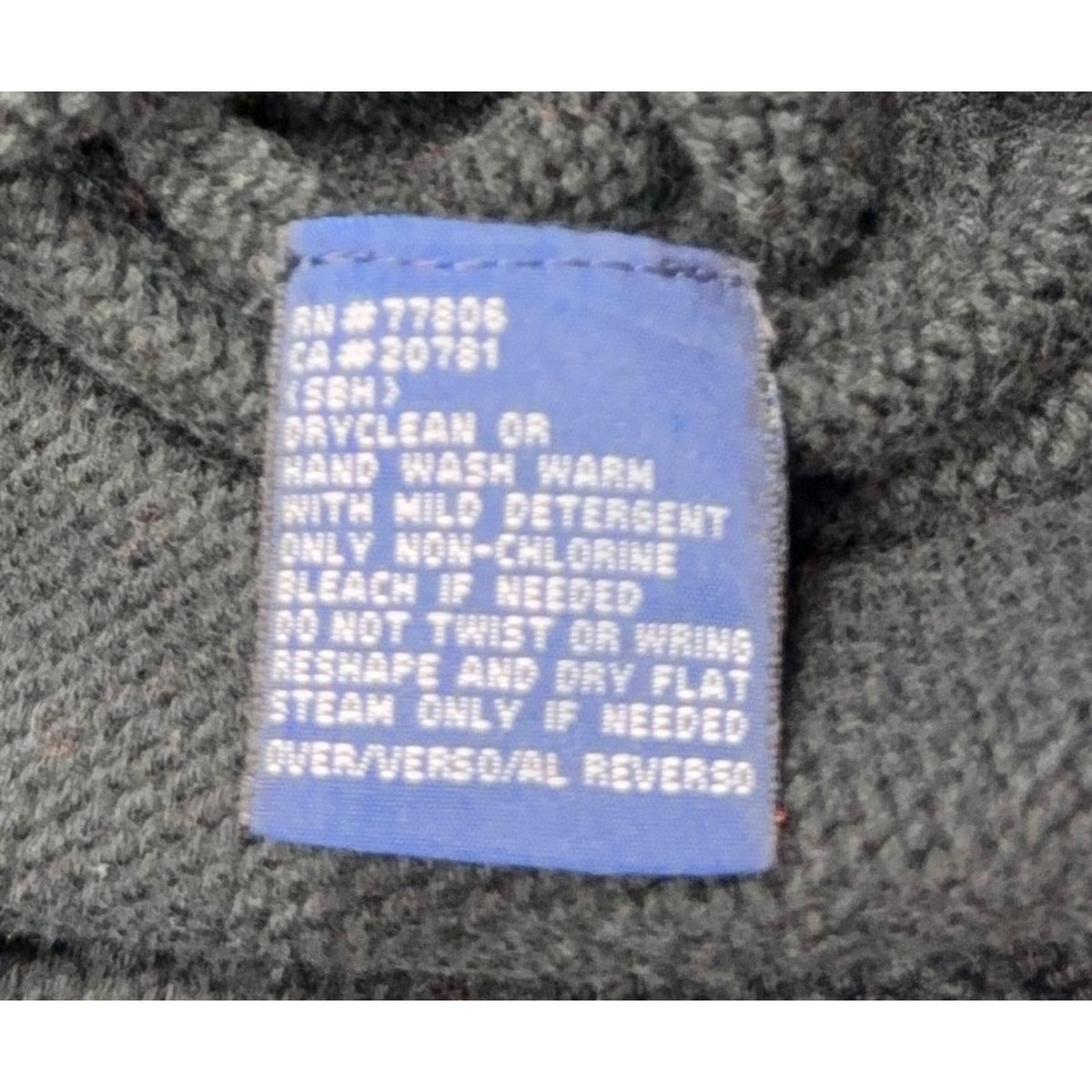 Second Half Supply Co, LLC blue care label on a dark green cotton knit sweater with washing instructions