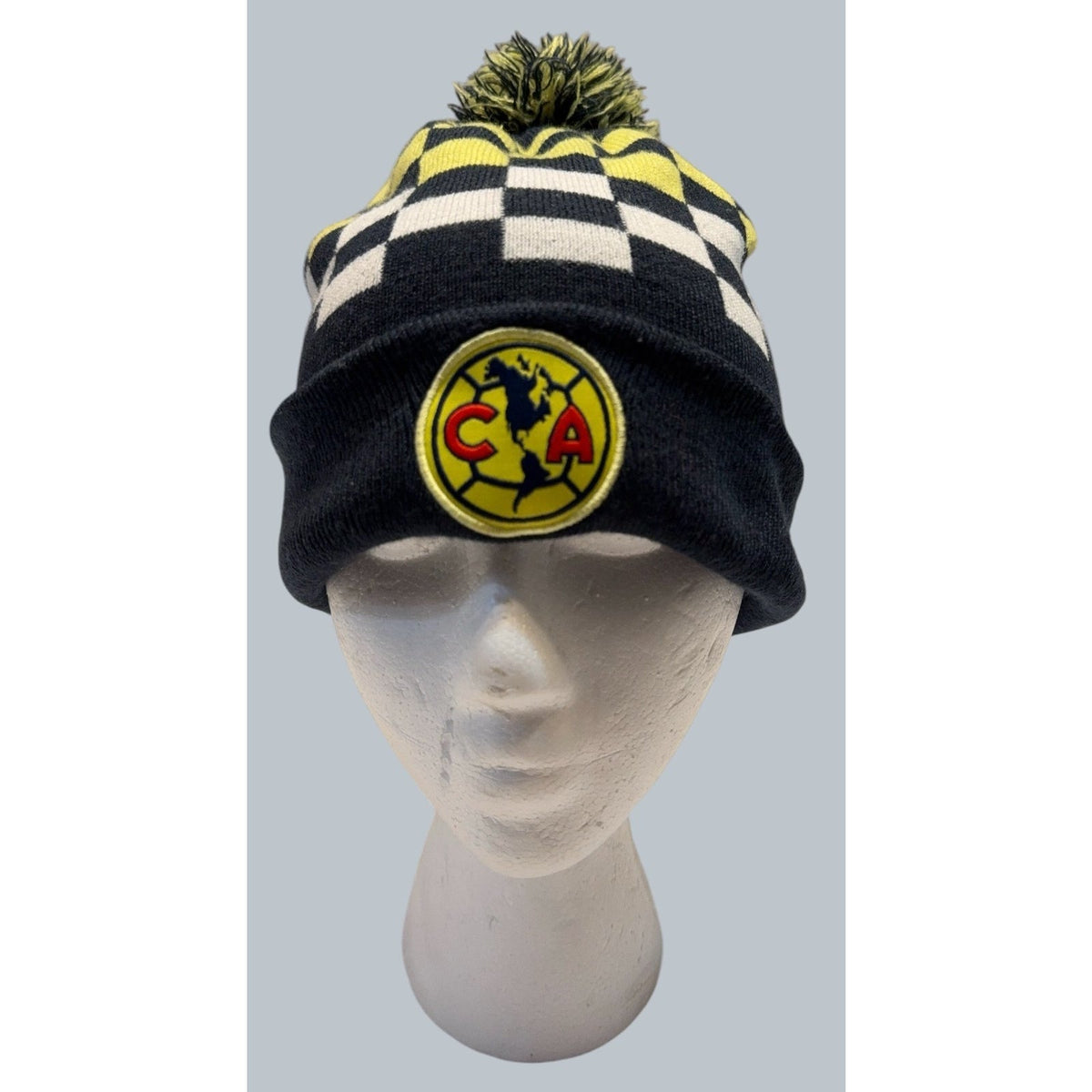Second Half Supply Co, LLC Club America cuffed knit beanie with navy, yellow, and white checkerboard and pom-pom.