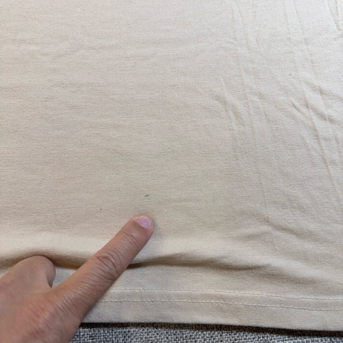 Second Half Supply Co, LLC cream cotton t-shirt showing a small blue mark on the fabric near the hem