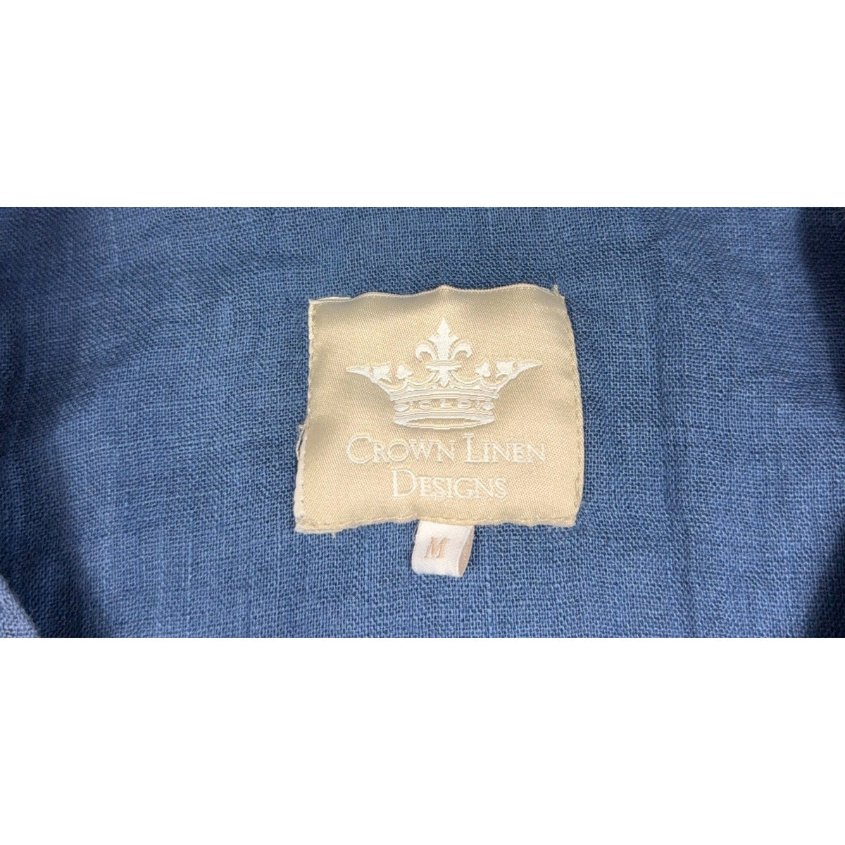 Second Half Supply Co, LLC Crown Linen Designs brand label on a textured muted denim blue fabric garment