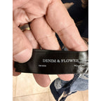 Second Half Supply Co, LLC Denim & Flower clothing brand fabric label held between fingers