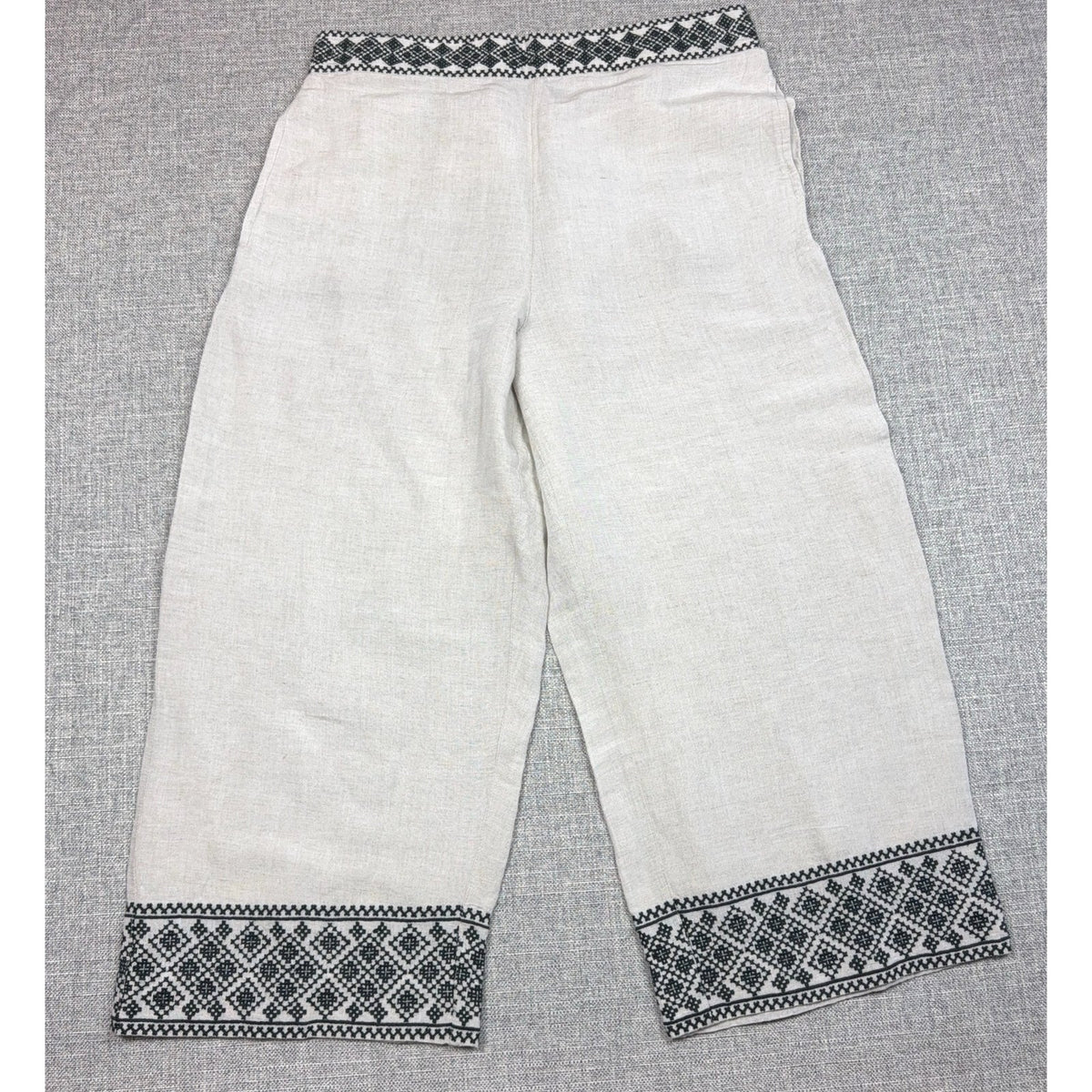 Second Half Supply Co, LLC cream wide-leg cropped pants with black geometric embroidery on the waistband and hems.