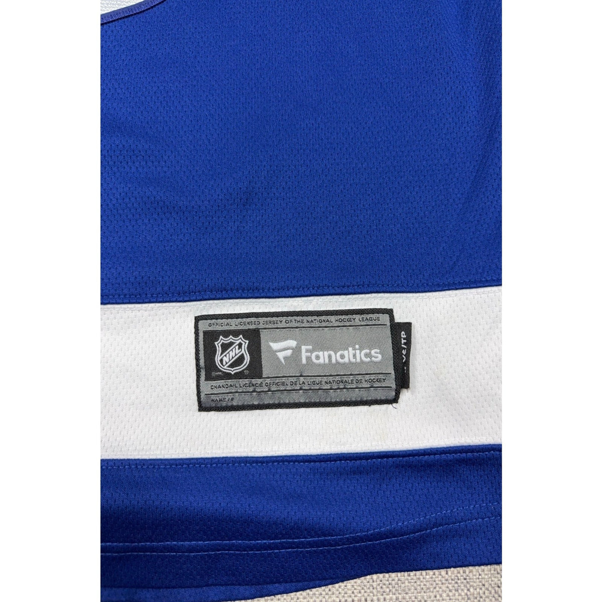 Second Half Supply Co, LLC Fanatics Tampa Bay Lightning jersey NHL tag detail on blue and white polyester fabric