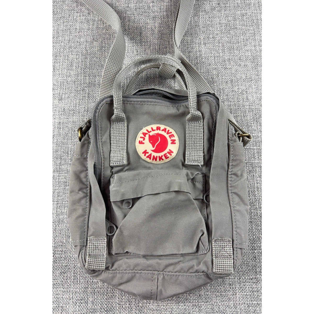 Second Half Supply Co, LLC Fjallraven Kanken Sling crossbody bag in fog gray with front zip pocket and top handles.