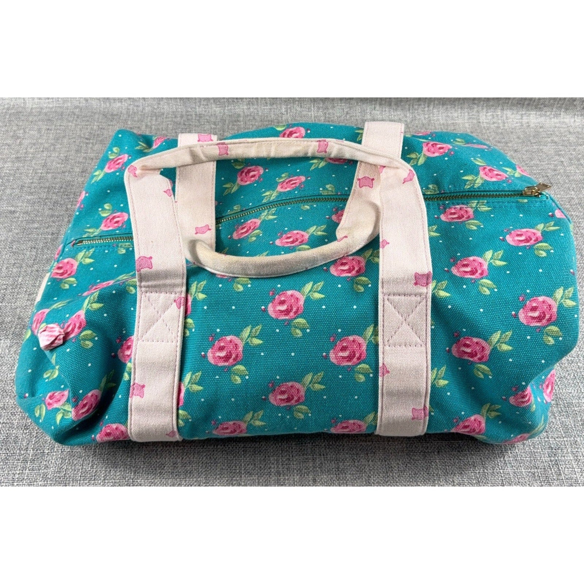 Second Half Supply Co, LLC floral canvas duffel bag in teal with pink rose print and pale pink handles.