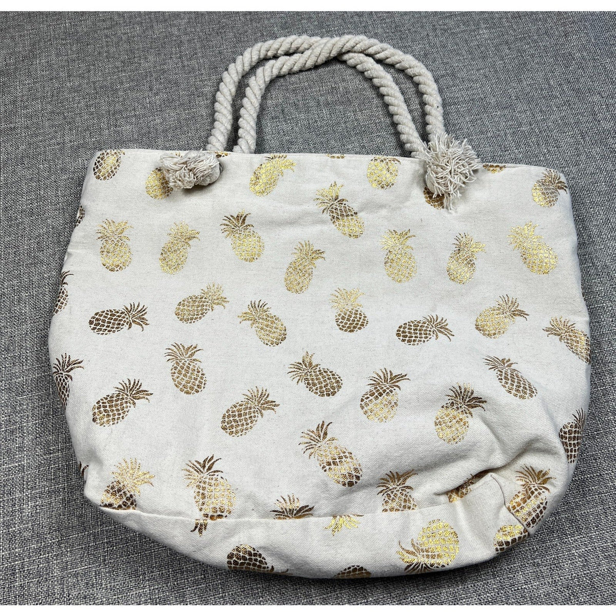 Second Half Supply Co, LLC cream canvas beach tote featuring a metallic gold pineapple pattern and twisted rope handles