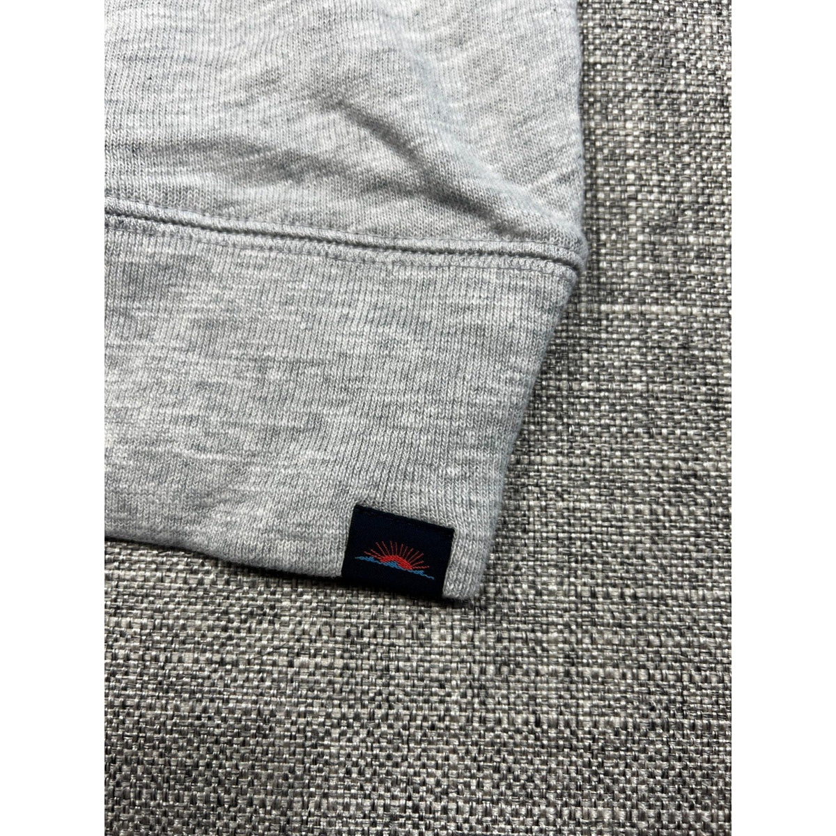 Second Half Supply Co, LLC gray organic cotton hoodie sleeve with ribbed cuff and small mountain sunrise logo patch