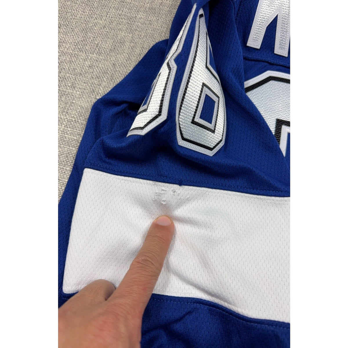 Second Half Supply Co, LLC blue and white hockey jersey sleeve showing fabric damage and snags on the white stripe