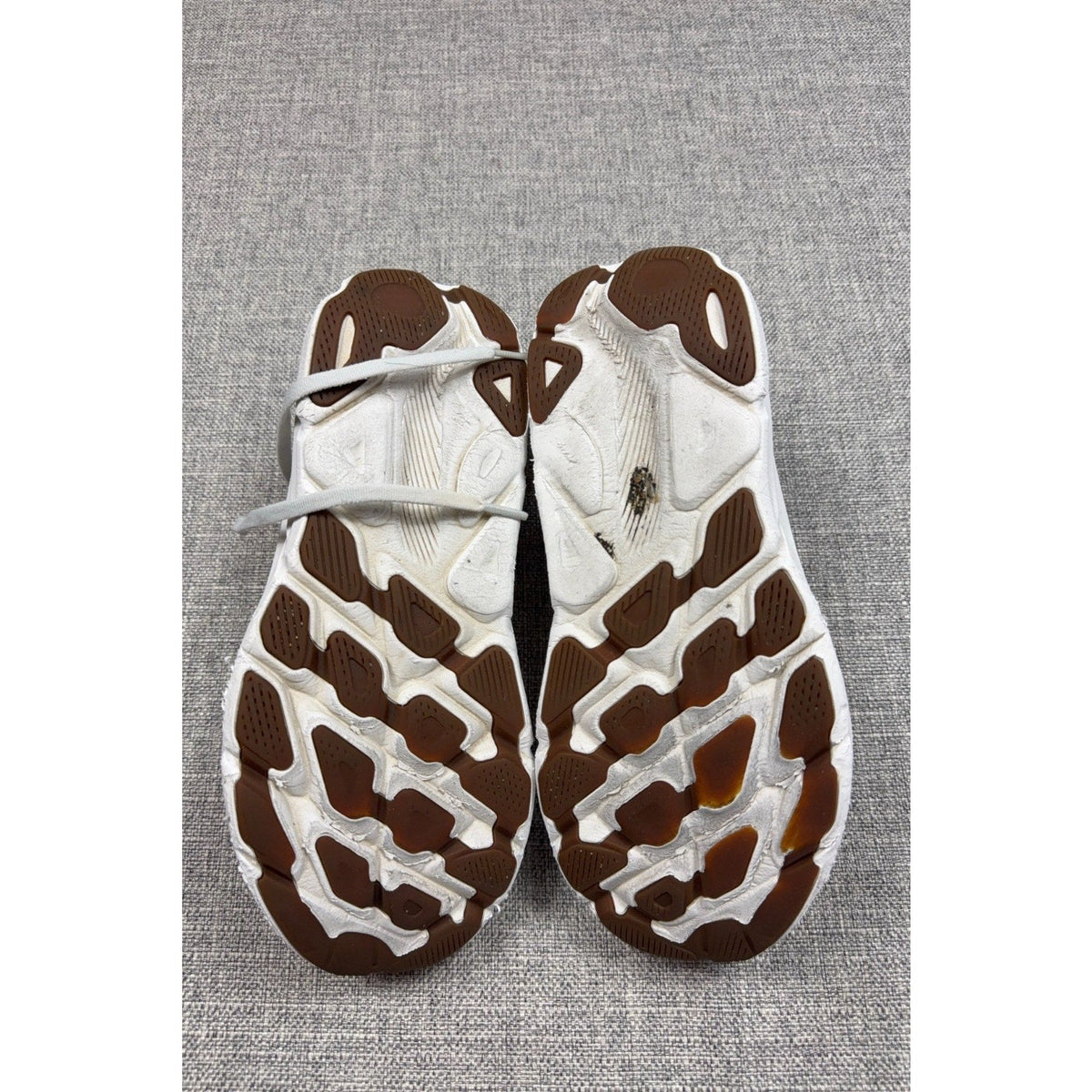 Second Half Supply Co, LLC HOKA Clifton 9 running shoes showing worn white midsoles and brown rubber traction outsoles