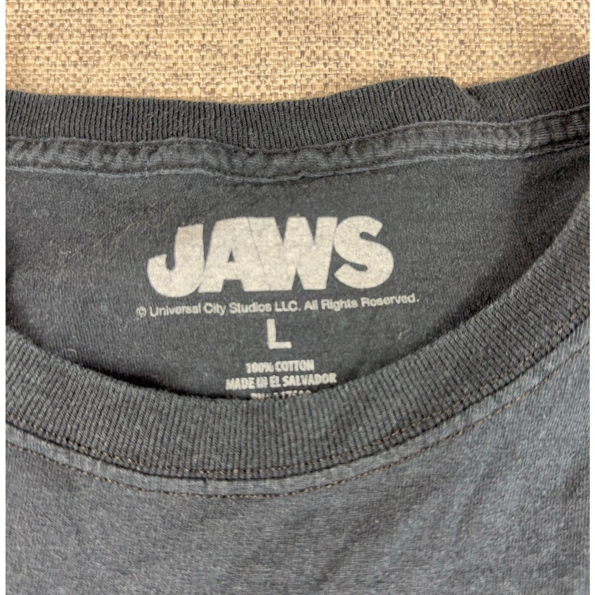 Second Half Supply Co, LLC black Jaws movie T-shirt neck label showing size Large and 100% cotton material