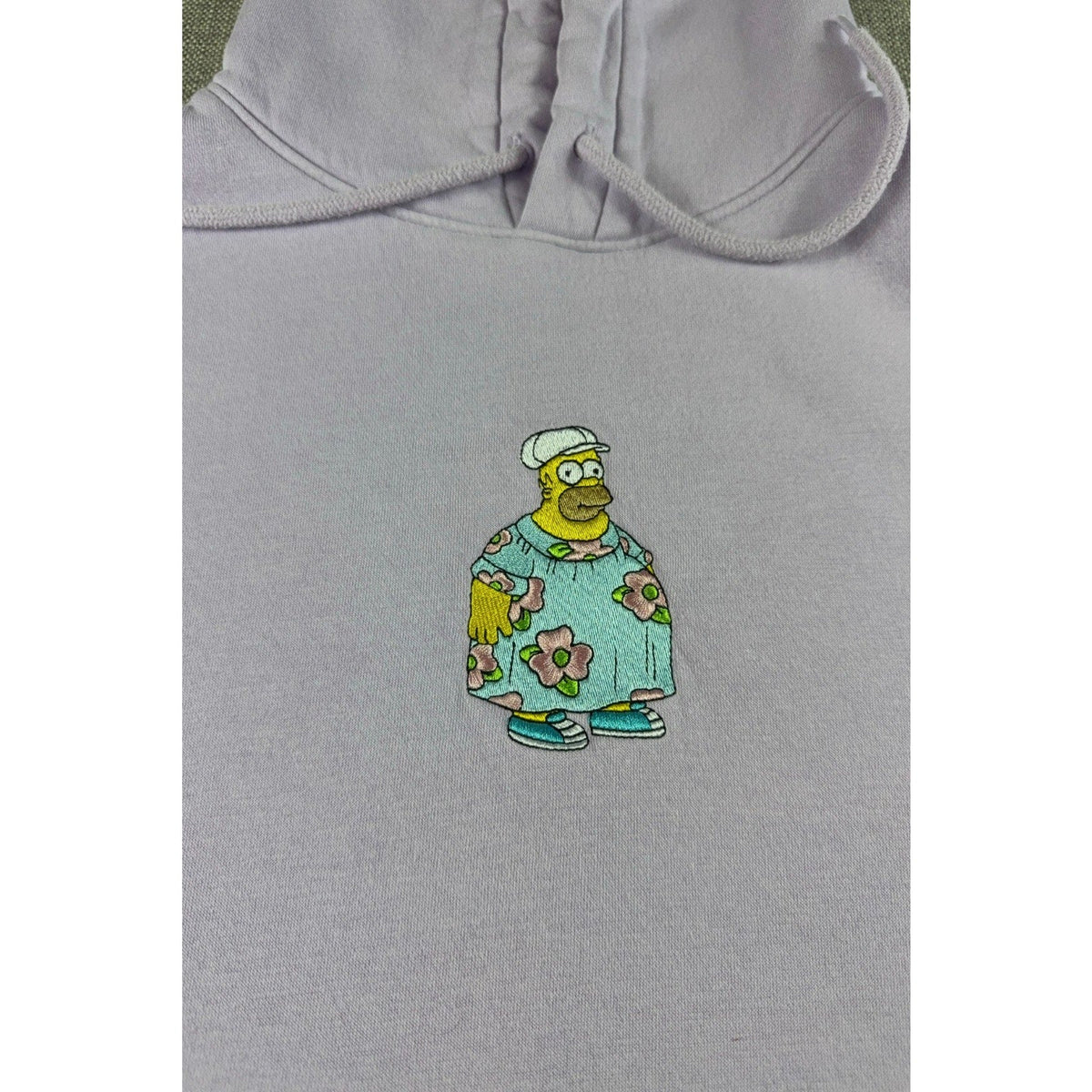 Second Half Supply Co, LLC lavender hoodie featuring an embroidered Homer Simpson graphic in a floral muumuu.