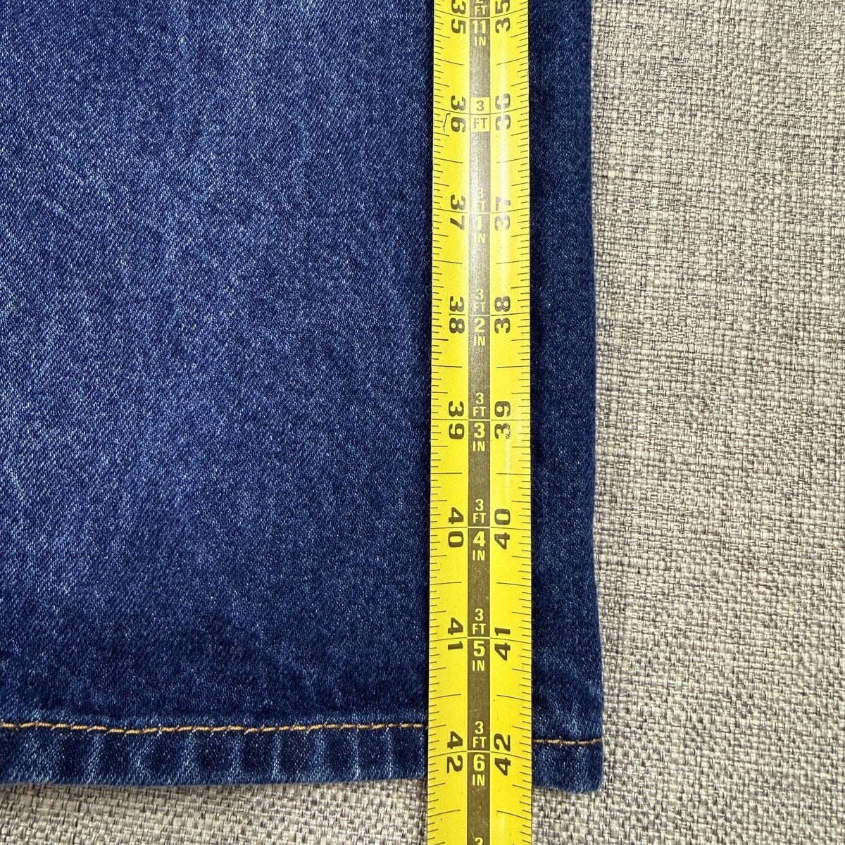 Second Half Supply Co, LLC Levi's 501 dark wash denim jeans being measured with a yellow tape measure to 42 inches.