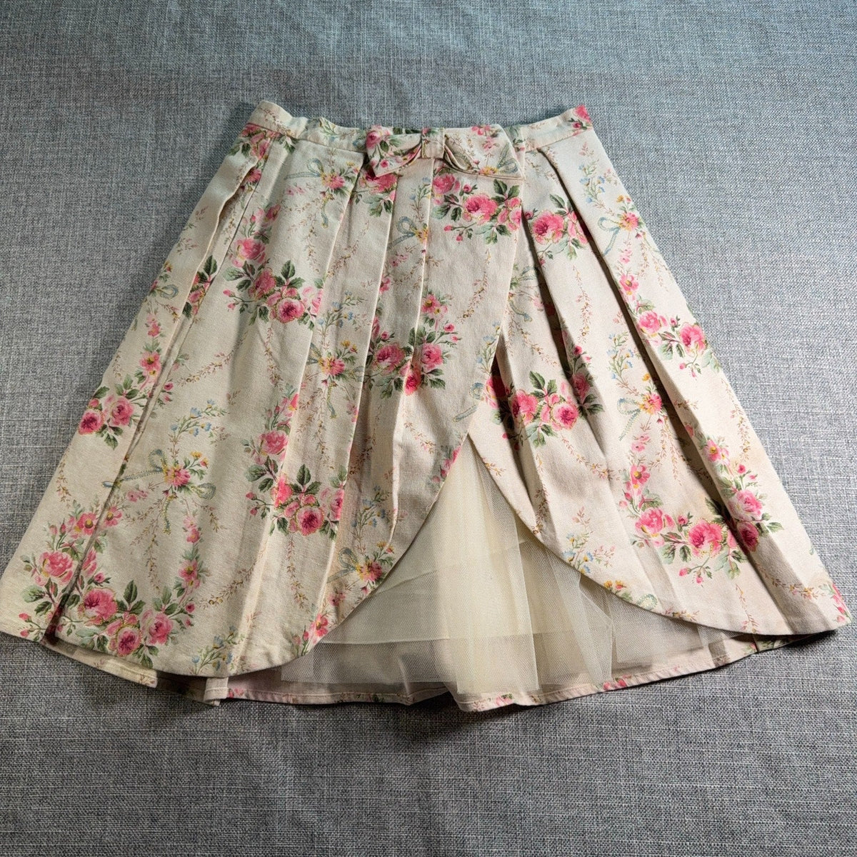 Second Half Supply Co, LLC Manoush cream floral pleated midi skirt with pink flowers, tulle lining, and bow detail.