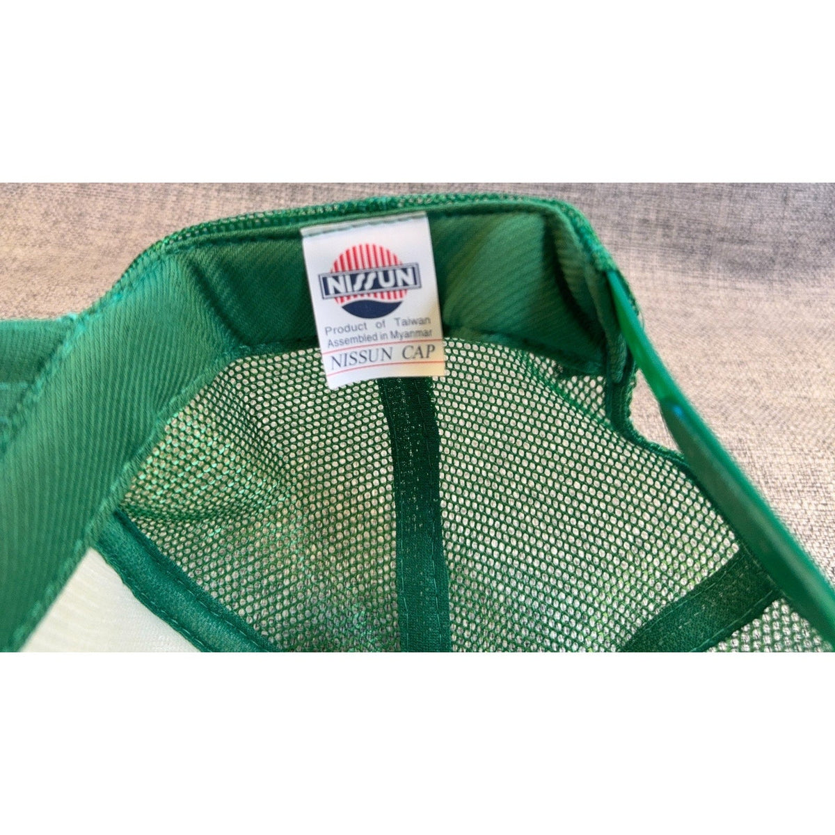 Second Half Supply Co, LLC green mesh trucker hat interior showing the Nissun brand label and manufacturing details