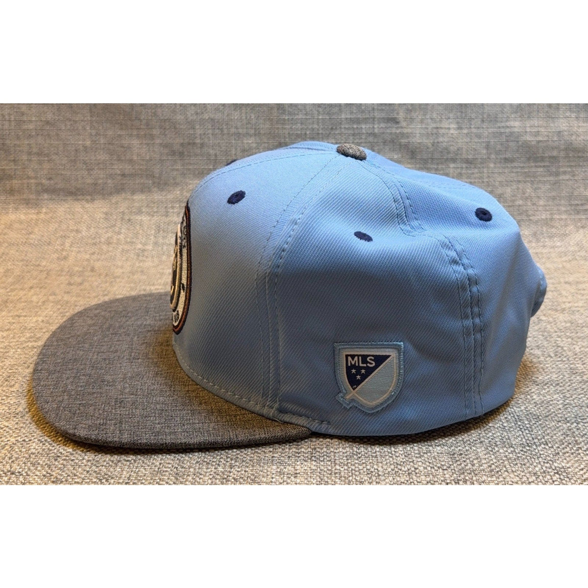 Second Half Supply Co, LLC Adidas NYCFC snapback hat with sky-blue crown, charcoal heather bill, and MLS side patch.