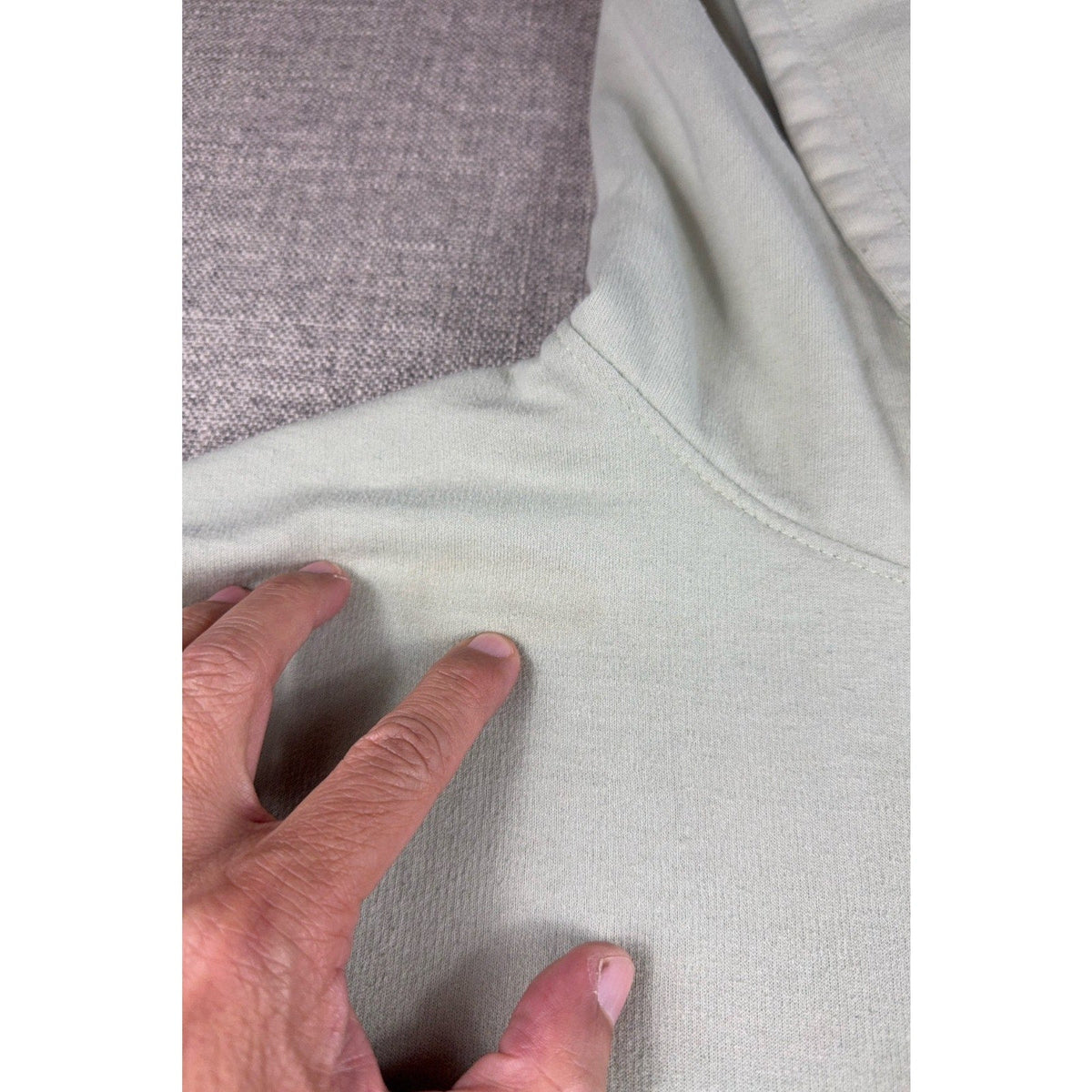 Second Half Supply Co, LLC sage green pullover hoodie showing a close-up of fabric discoloration on the shoulder