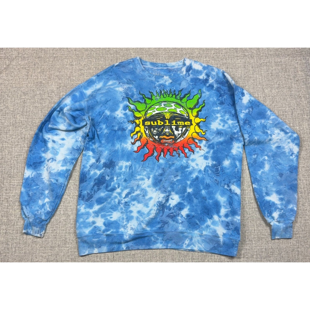 Second Half Supply Co, LLC blue tie-dye Sublime crewneck sweatshirt with a colorful sun graphic and ribbed trim.
