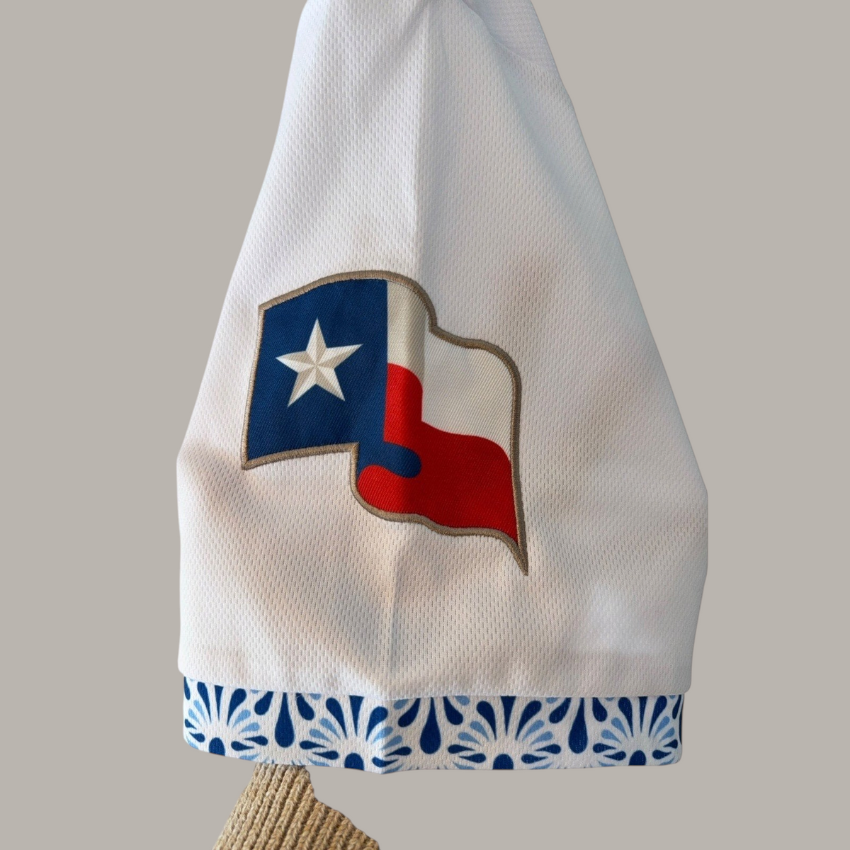 Second Half Supply Co, LLC white mesh baseball jersey sleeve with Texas flag patch and blue Talavera-inspired trim.