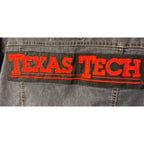 Second Half Supply Co, LLC denim jacket back view featuring a large red Texas Tech embroidered patch on black fabric