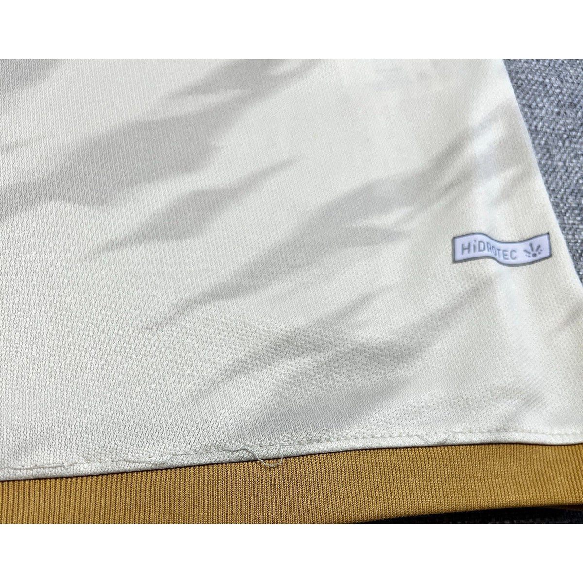 Second Half Supply Co, LLC cream Universitario 2025 home jersey showing Hidrotec fabric detail and hem stitching