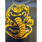 Second Half Supply Co, LLC vintage black Cobra Kai t-shirt with distressed yellow snake graphic and worn-in texture.