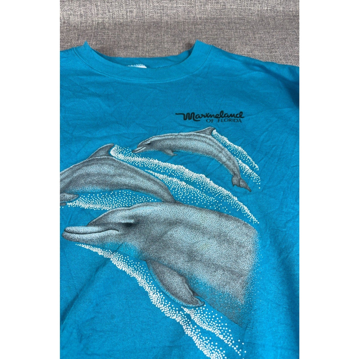 Second Half Supply Co, LLC vintage 90s teal crewneck sweatshirt featuring a Marineland of Florida dolphin graphic.