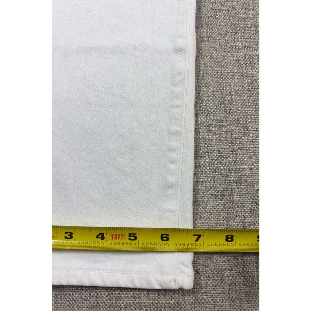 Second Half Supply Co, LLC white denim jeans leg opening measurement showing seven inches on a yellow tape measure